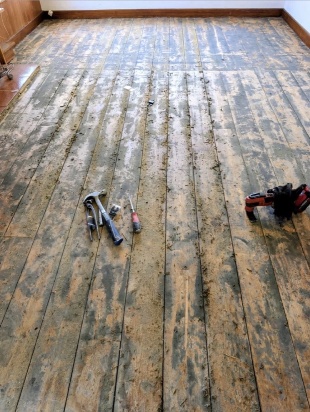 Stripped hardwood floor mid-job, tools on the boards